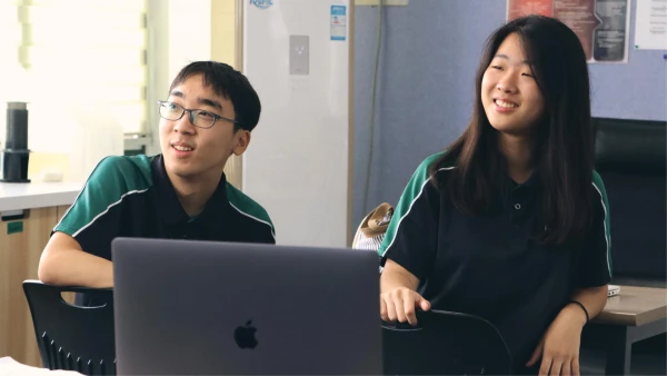 International School of Wuxi High School students smiling in front of a computer