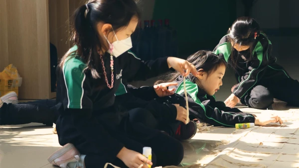 three young female students at international school of wuxi learning how to make art