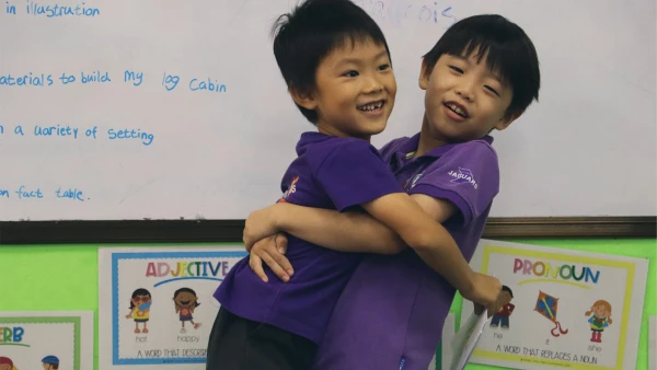 two young male students hugging inside international school of wuxi with purple shirts on